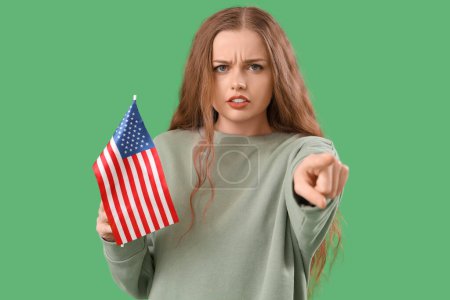 Junge Frau mit USA-Fahne zeigt auf den Betrachter auf grünem Hintergrund. Anschuldigungskonzept