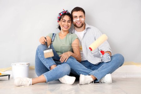 Photo for Beautiful young happy couple with paint roller and brush doing repair in new house - Royalty Free Image