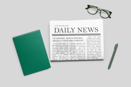 Newspaper with pen and glasses on grey background. Top view