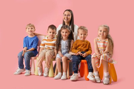 Photo for Little children with nursery teacher sitting on pink background - Royalty Free Image