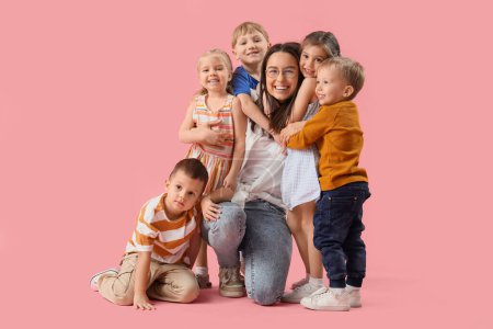 Little children hugging nursery teacher on pink background