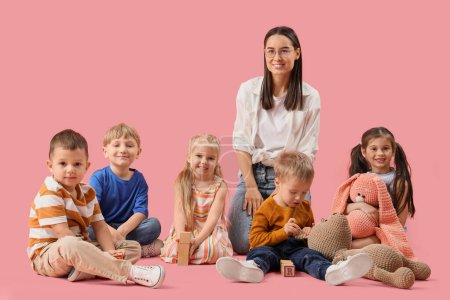 Photo for Little children with toys and nursery teacher on pink background - Royalty Free Image