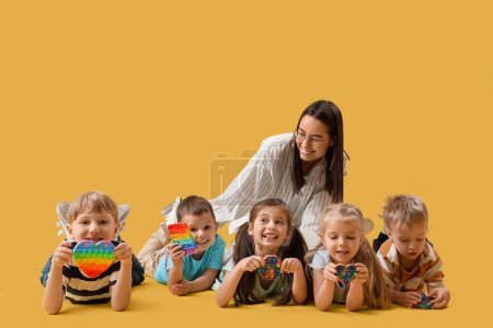 Photo for Little children with nursery teacher lying on yellow background - Royalty Free Image