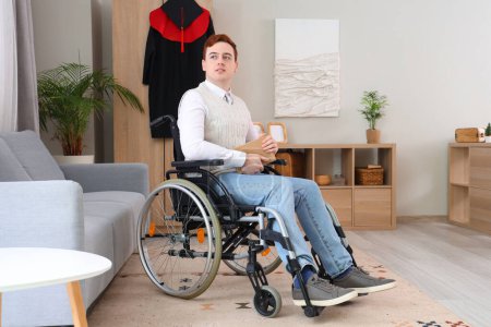 Male graduate in wheelchair with book at home