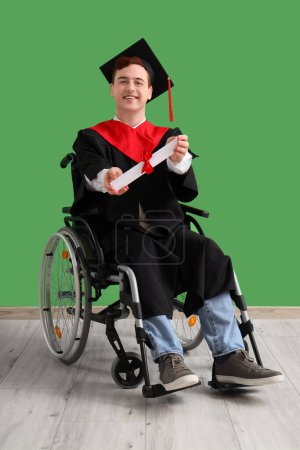 Male graduate in wheelchair with diploma near green wall