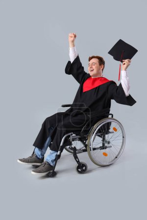 Glücklicher männlicher Absolvent im Rollstuhl vor hellem Hintergrund