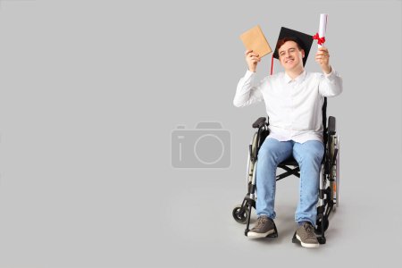 Männlicher Absolvent im Rollstuhl mit Buch und Diplom auf hellem Hintergrund