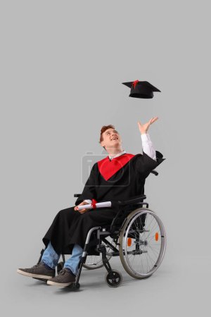 Männlicher Absolvent im Rollstuhl mit Diplom-Wurfhut auf hellem Hintergrund