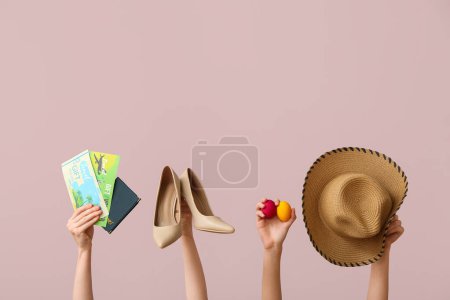 Foto de Manos femeninas sosteniendo cupones de regalo con zapatos, sombrero y huevos de Pascua sobre fondo rosa. Concepto de viaje - Imagen libre de derechos