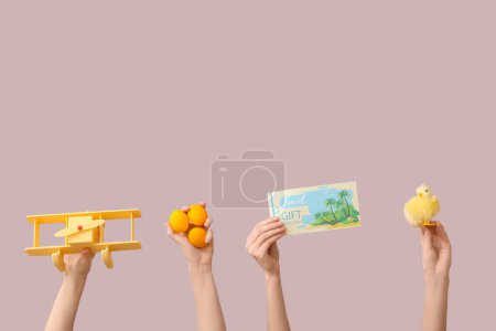 Foto de Manos femeninas sosteniendo vales de regalo con avión de juguete, pollo y huevos de Pascua sobre fondo rosa. Concepto de viaje - Imagen libre de derechos