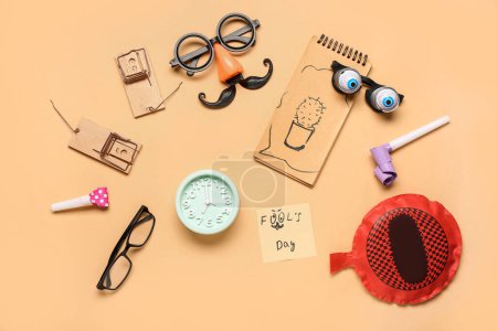 Funny glasses with alarm clock, whoopee cushion and mousetraps on beige background. April Fool Day