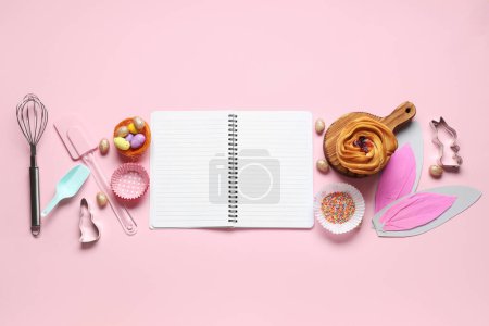 Téléchargez les photos : Bloc-notes vierge pour recettes avec pain sucré, décor de Pâques et outils de cuisson sur fond rose - en image libre de droit