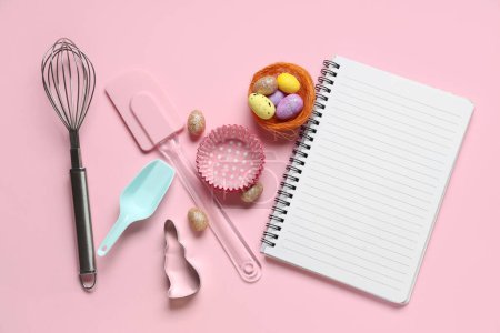 Téléchargez les photos : Bloc-notes vierge pour recettes avec oeufs de Pâques et outils de cuisson sur fond rose - en image libre de droit