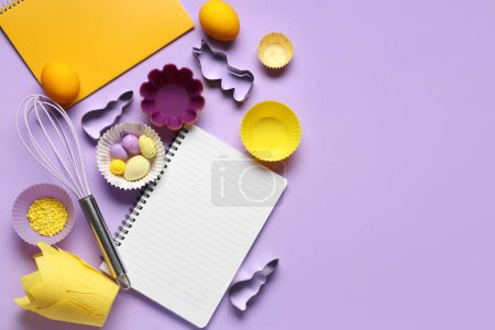 Téléchargez les photos : Bloc-notes vierges pour recettes avec oeufs de Pâques et outils de cuisson sur fond lilas - en image libre de droit