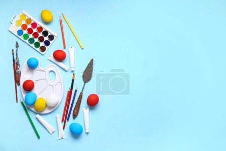 Foto de Acuarelas, huevos de Pascua, paleta y pinceles sobre fondo de color - Imagen libre de derechos