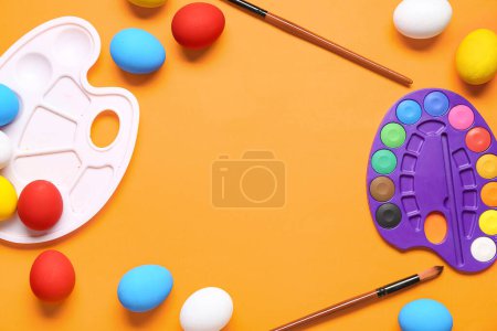 Foto de Marco hecho de paletas de pintura, huevos de Pascua y pinceles sobre fondo de color. Concepto Pascua. - Imagen libre de derechos
