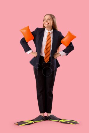 Lustige Geschäftsfrau mit aufblasbaren Ärmeln und Flossen auf rosa Hintergrund
