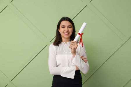 Photo for Happy smiling female student with diploma on green wooden background - Royalty Free Image