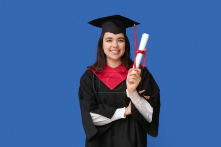 Photo for Happy female graduating student with diploma on blue background - Royalty Free Image