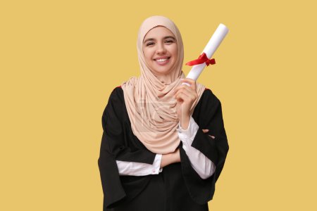 Photo for Happy Muslim female graduating student with diploma on yellow background - Royalty Free Image