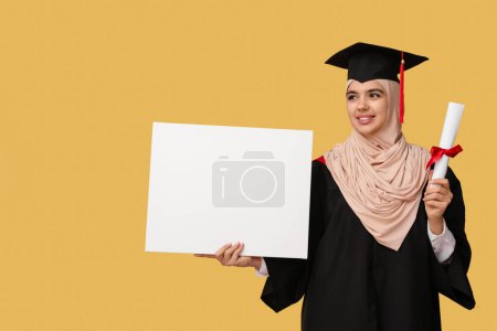 Photo for Happy Muslim female graduating student with diploma and blank poster on yellow background - Royalty Free Image