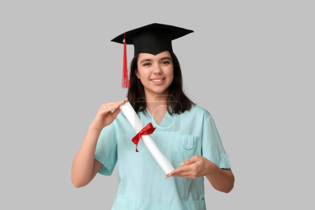 Photo for Happy female medical student in graduation hat with diploma on white background - Royalty Free Image