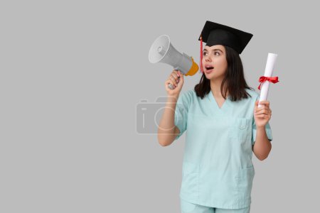 Photo for Female medical student in graduation hat with megaphone and diploma on white background - Royalty Free Image