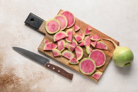 Wooden board with cut ripe watermelon radishes on grunge background