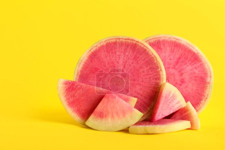 Cut ripe watermelon radish on yellow background