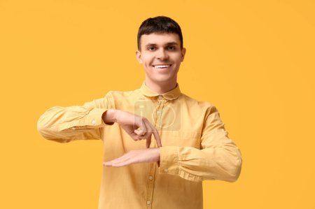 Junger taubstummer Mann benutzt Gebärdensprache auf gelbem Hintergrund