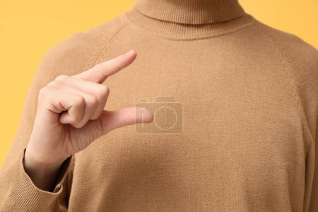 Junger taubstummer Mann mit Zeichensprache auf gelbem Hintergrund, Nahaufnahme