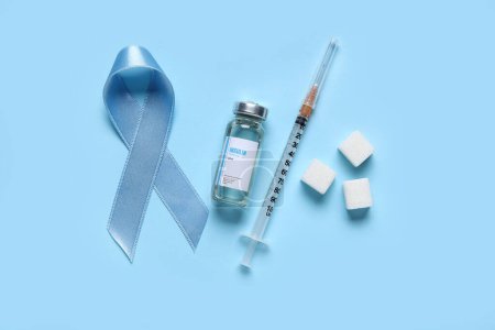 Bewusstseinsband mit Insulin, Spritze und Zuckerwürfeln auf blauem Hintergrund. Diabetes-Konzept