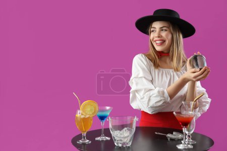 Female bartender with shaker at table on purple background