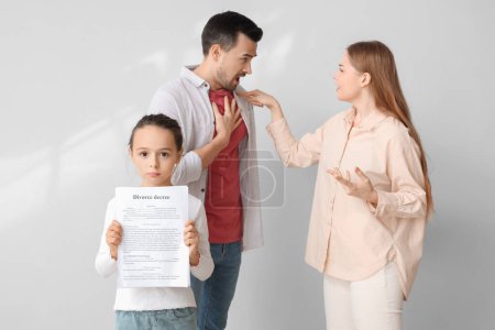 Sad little girl with divorce decree and her arguing parents on light background