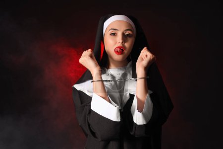 Photo for Naughty nun with handcuffs on dark background - Royalty Free Image