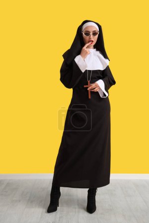 Freche Nonne mit Sonnenbrille in der Nähe der gelben Wand