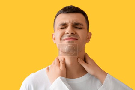 Endocrinologue examinant la glande thyroïde du jeune homme sur fond jaune, gros plan