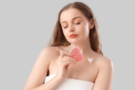 Beautiful young woman with heart made of cream and sponge on light background, closeup