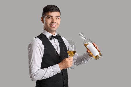 Photo for Young sommelier with glass and bottle of wine on grey background - Royalty Free Image