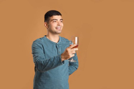 Photo for Young man with glass of pink wine on beige background - Royalty Free Image