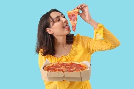 Junge Frau mit leckerer Pfefferoni-Pizza auf blauem Hintergrund