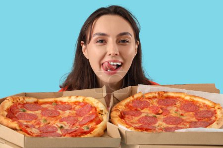 Junge Frau mit leckerer Pfefferoni-Pizza auf blauem Hintergrund, Nahaufnahme