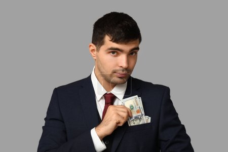 Junger Geschäftsmann mit Bestechungsgeld in der Tasche auf hellem Hintergrund, Nahaufnahme