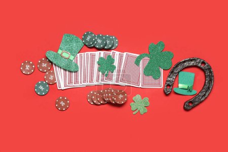 Fichas de póquer, cartas, sombrero de duende y tréboles de la suerte sobre fondo rojo. Celebración del Día de San Patricio