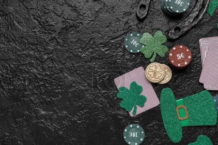 Poker chips, cards, lucky clovers and leprechaun's hat on black grunge background. St. Patrick's Day celebration