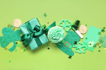Gift box with cupcake and decor for St. Patrick's Day on green background