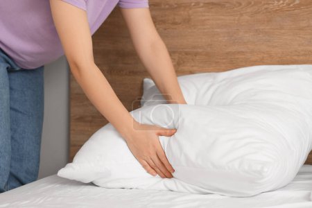 Photo for Woman putting pillow on bed in bedroom, closeup - Royalty Free Image