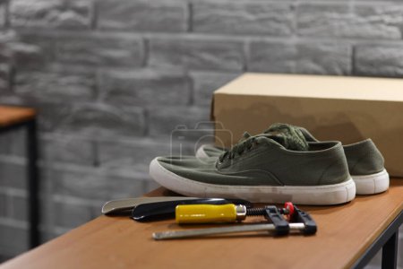 Sneakers with tools on shelf in shoemaker's workshop, closeup