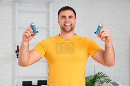 Téléchargez les photos : Jeune homme sportif avec inhalateurs dans la salle de gym - en image libre de droit