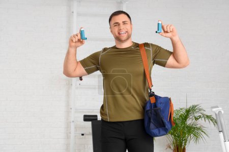 Téléchargez les photos : Jeune homme sportif avec sac et inhalateurs dans la salle de gym - en image libre de droit
